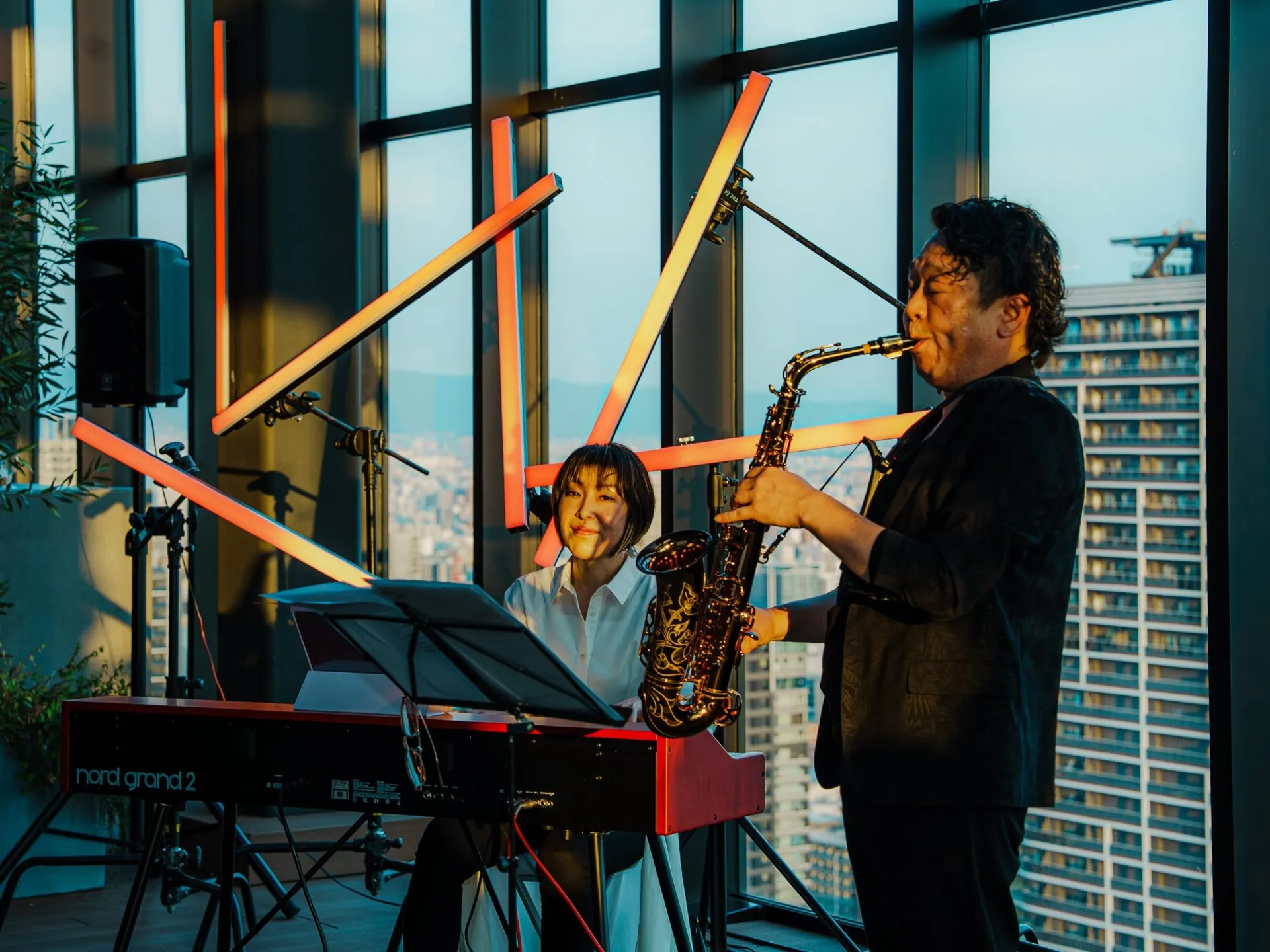 夕日の差す高層ラウンジでのサックスとピアノの演奏